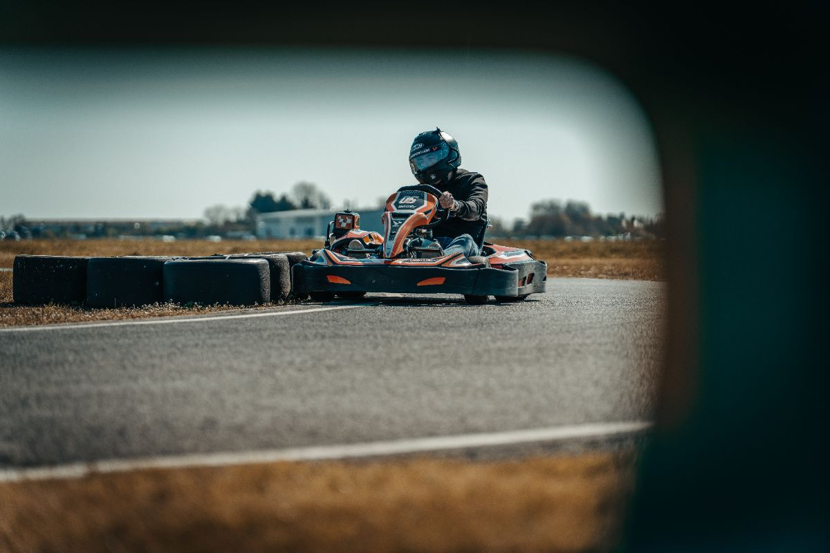 High-speed go-kart racing action on track, showcasing competitive drivers maneuvering sharp turns under sunny skies