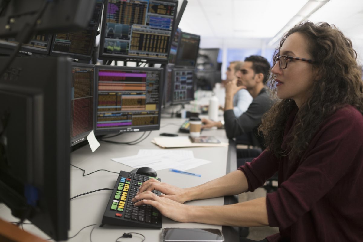 Bloomberg trading terminal with live market data and charts, trader analyzing statistics for strategic decision-making