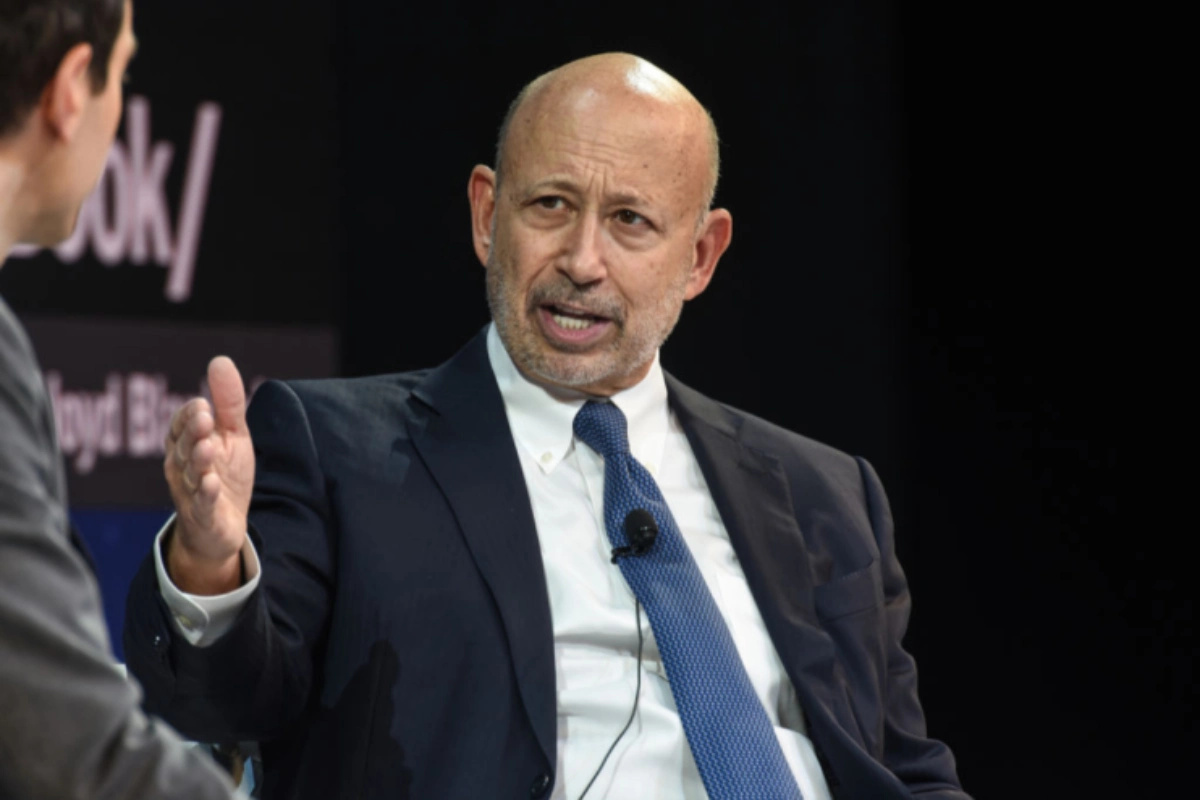 Former Goldman Sachs CEO Lloyd Blankfein speaking at a business conference, dressed in a suit and tie, addressing the audi...